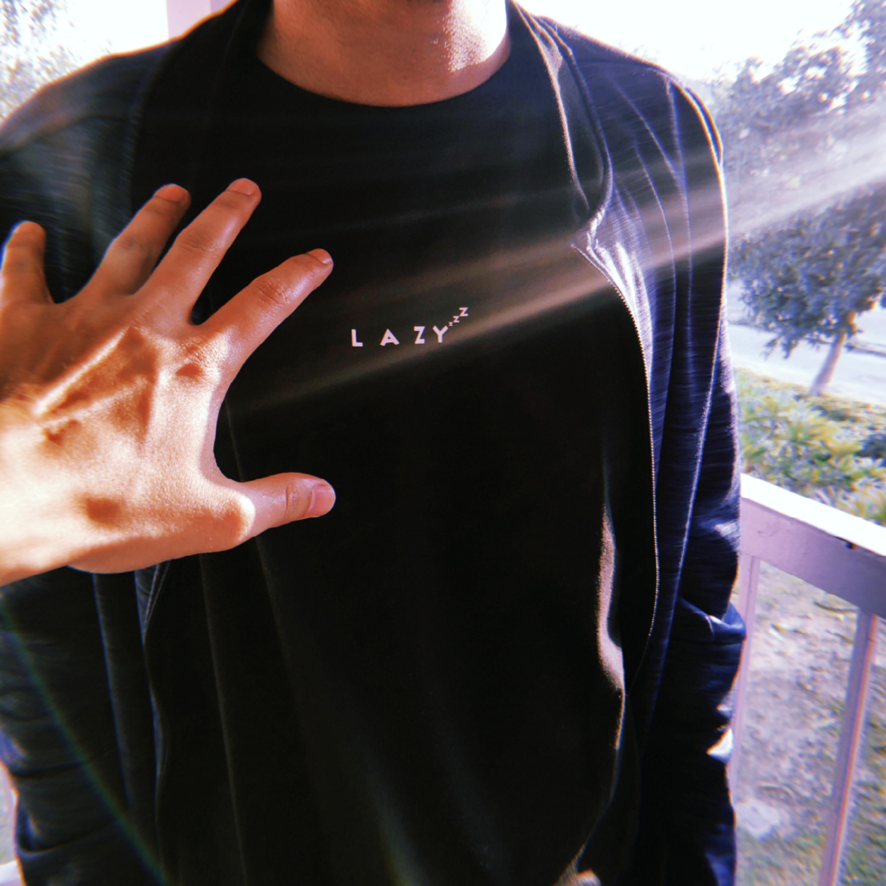 Lucid - Brainsickbiscuit. Hand reaching out to man wearing black t-shirt with lazy written in white.